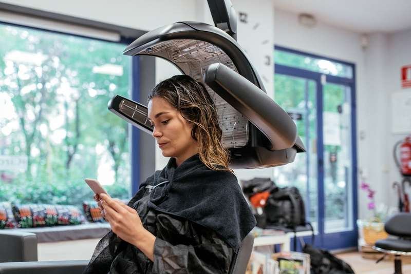 Client under dryer using phone